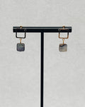 Abalone Gold Square Studs with square gold frames and iridescent abalone stone drops displayed on a stand