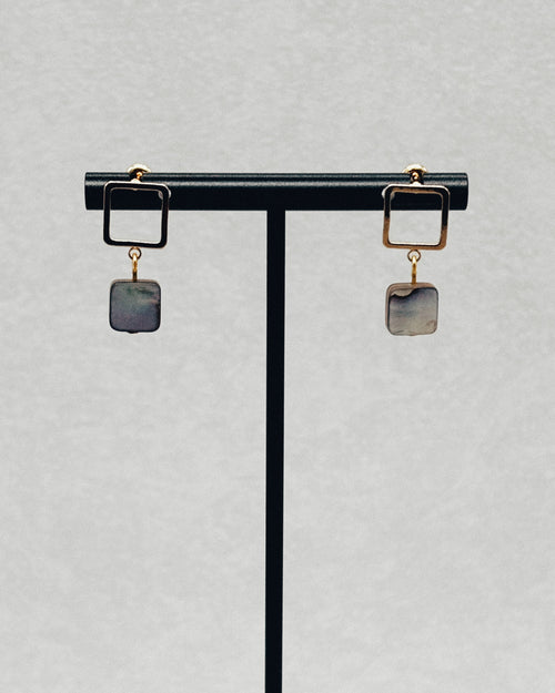 Abalone Gold Square Studs with square gold frames and iridescent abalone stone drops displayed on a stand