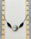 Black Lip Swirl Necklace with silver spiral centerpiece flanked by dark elongated beads on a silver chain