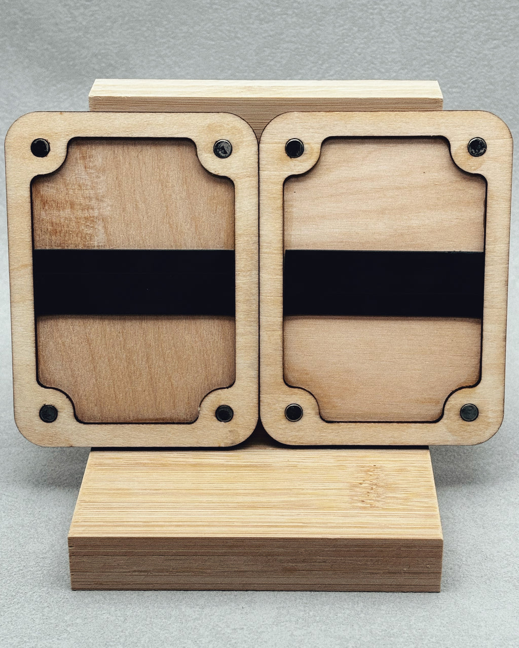 Needle Keepers wooden display holder with curved corner cutouts and black bands on light natural wood background