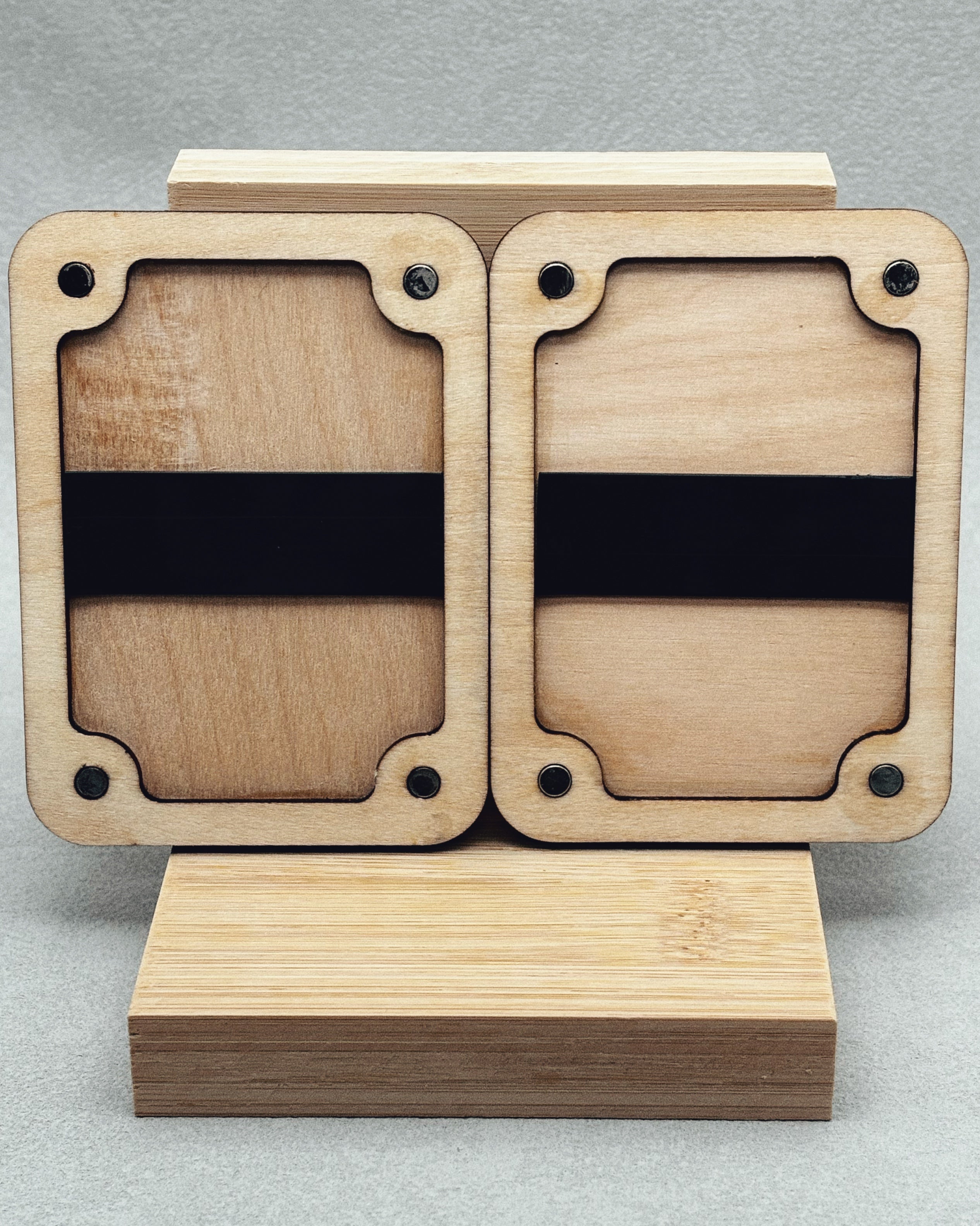 Needle Keepers wooden display holder with curved corner cutouts and black bands on light natural wood background
