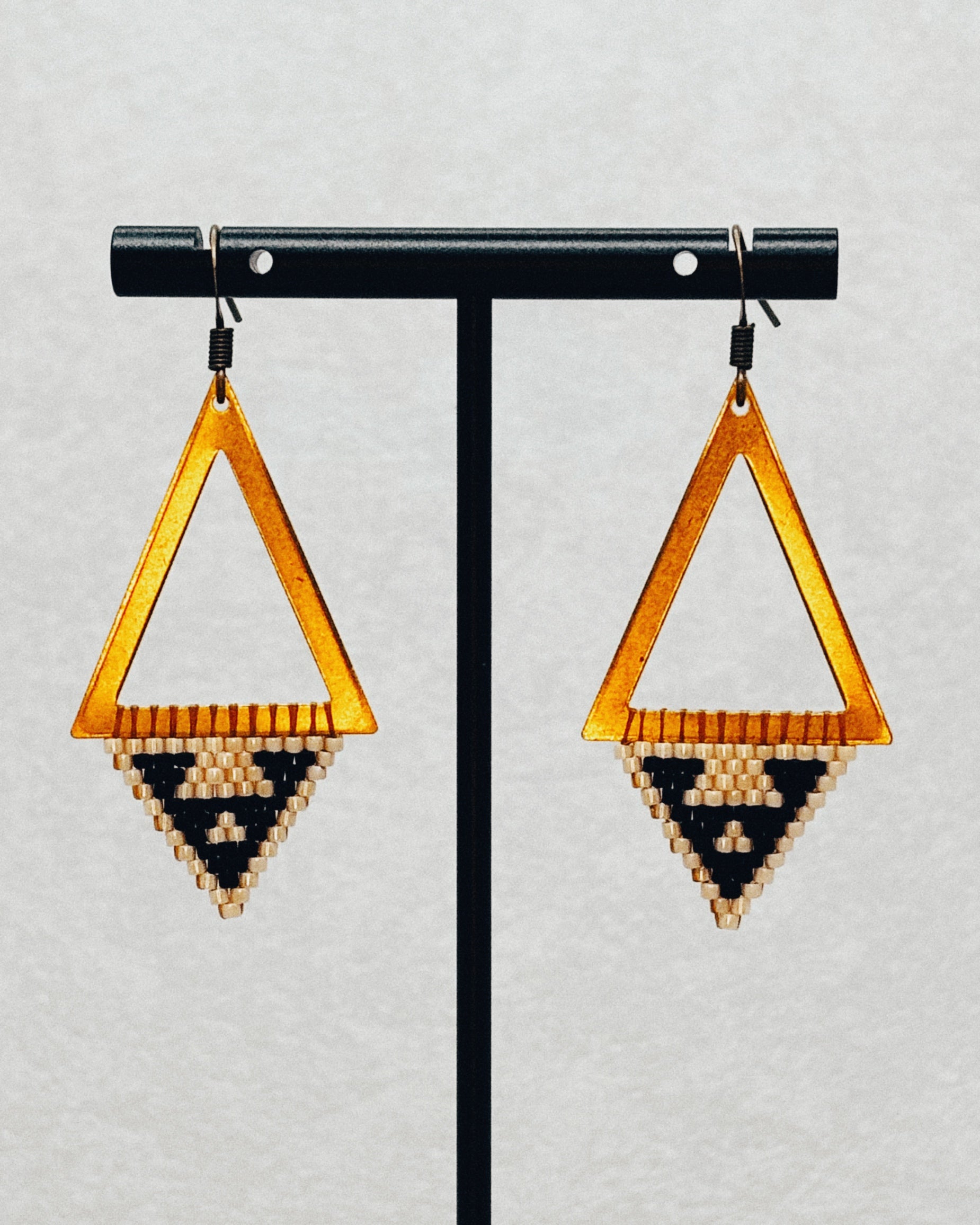 Bronze Triangle Dangles with warm bronze open frames and handmade black and cream beaded geometric triangle patterns