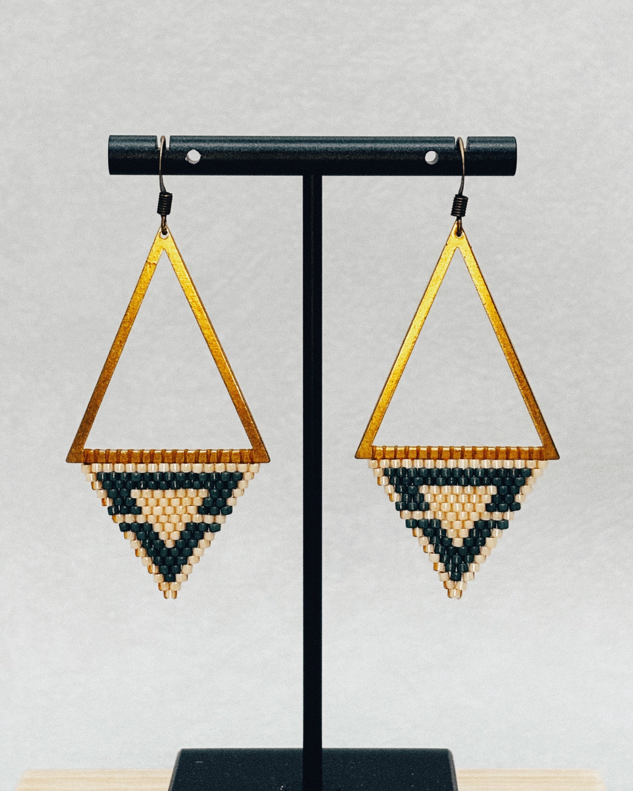 Bronze Triangle Dangles featuring gold-tone open frames with black and cream handmade beadwork in geometric patterns