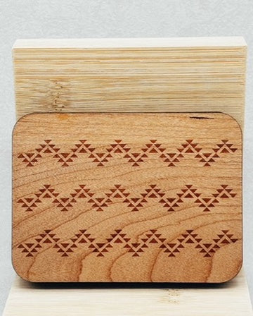 Needle Keepers featuring a carved wood design with repeating geometric indigenous-inspired triangle patterns