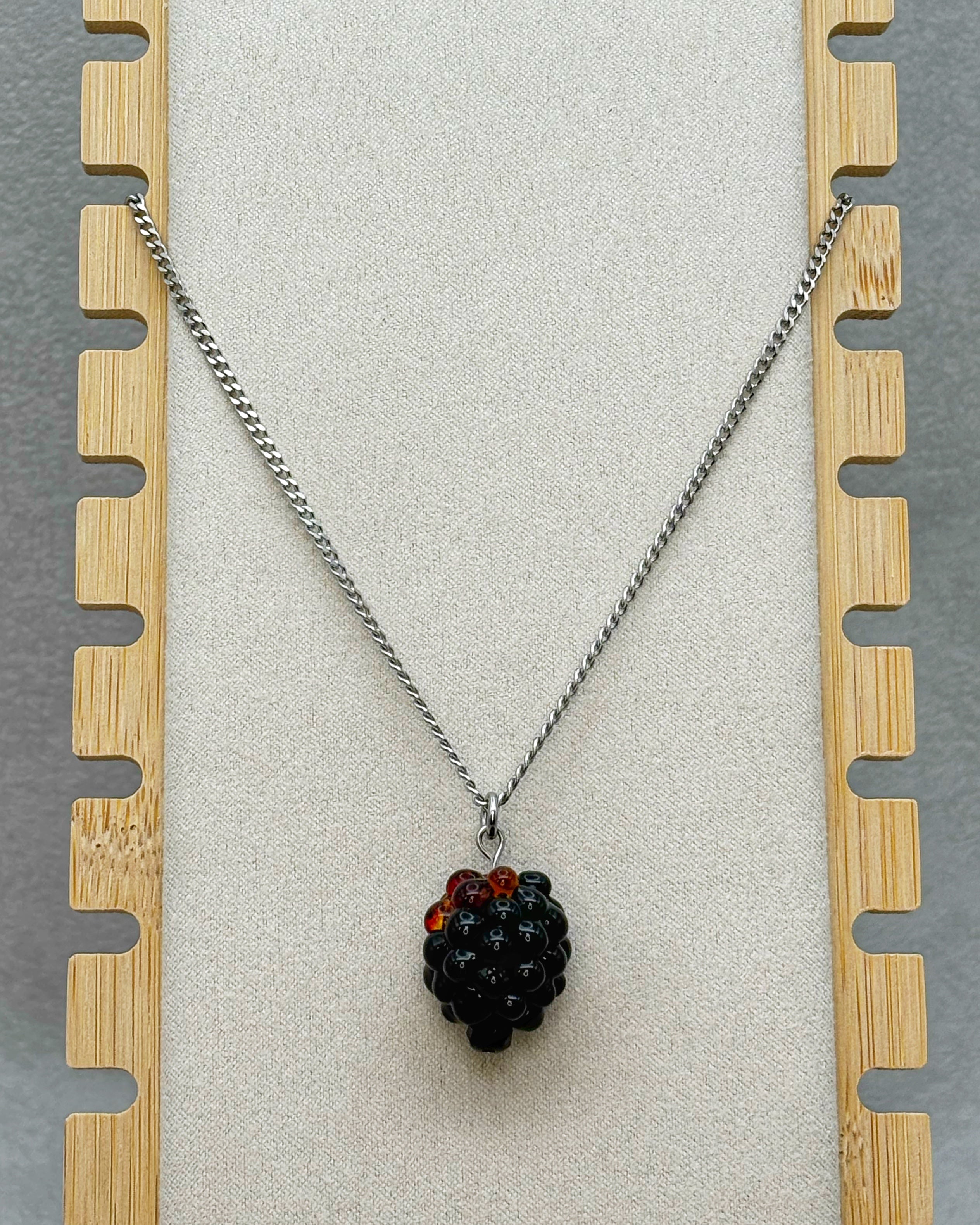 Blackberry Necklace featuring a detailed black and red berry pendant on a silver-tone chain display