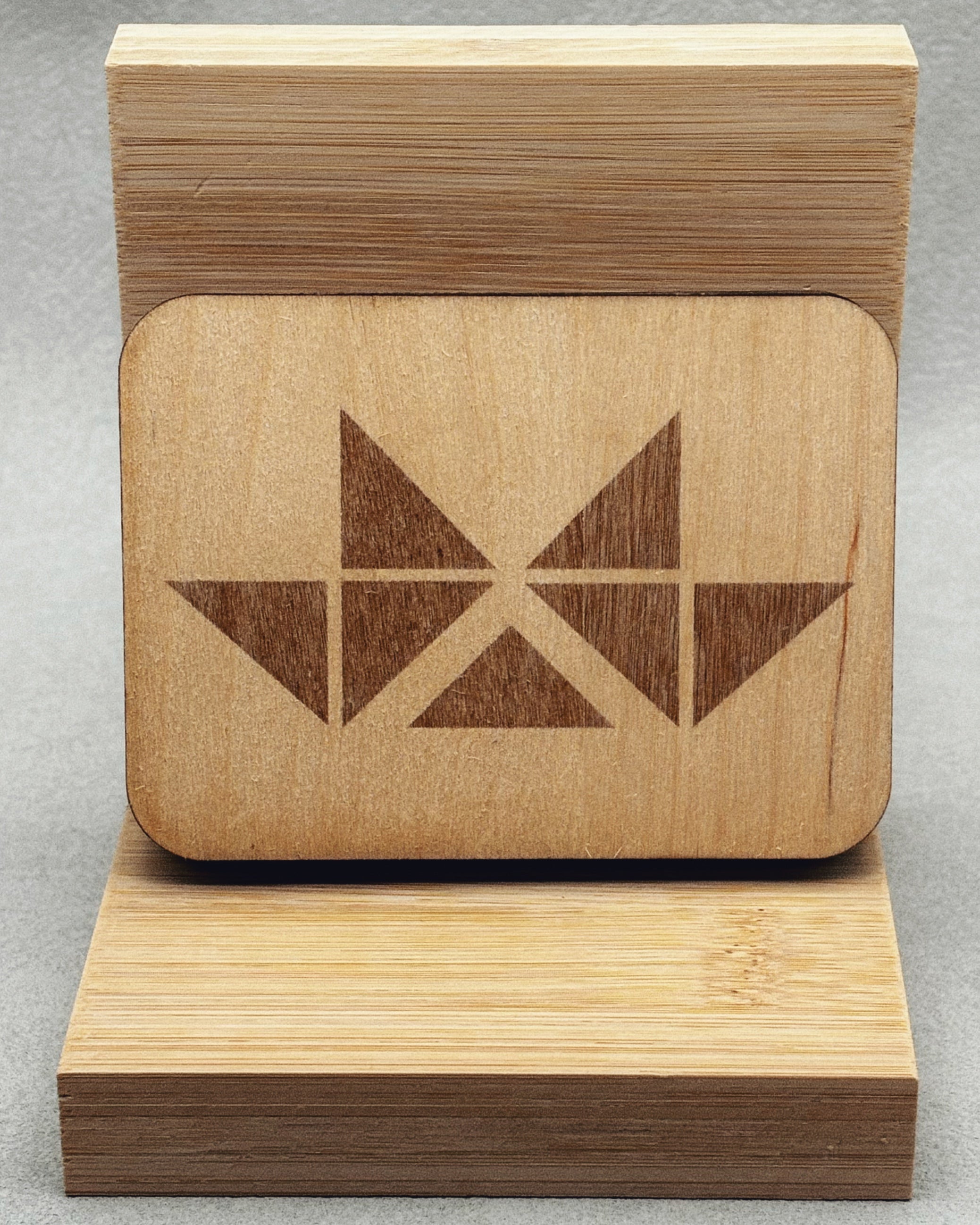Needle Keepers wooden box with laser-engraved dark geometric pattern on a smooth light wood surface displayed on a wood stand