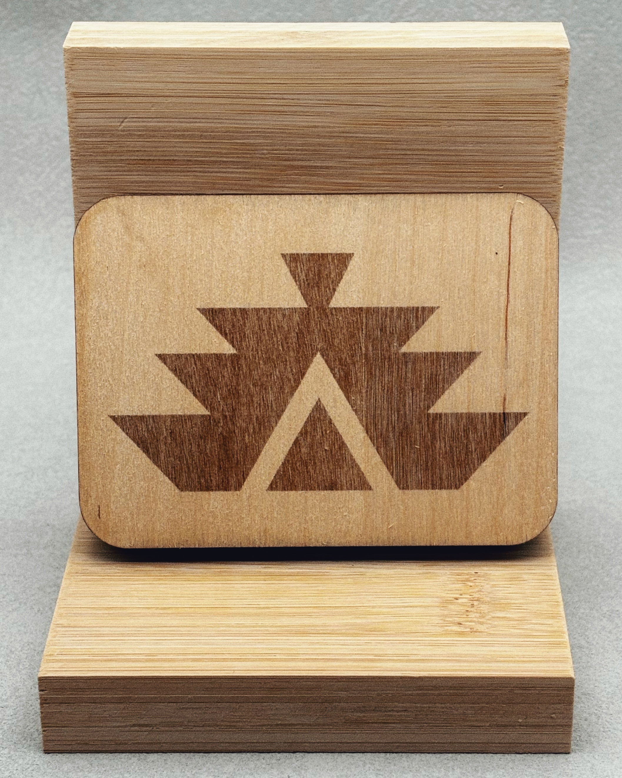 Needle Keepers wooden box with laser-etched dark native geometric design on light wood displayed on bamboo stand