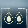 Hammered Gold Teardrop Dangles with White Abalone featuring luminous abalone teardrops in hammered gold frames on clear display stand