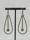 Hammered Bronze Teardrop Dangles with Faceted Abalone hanging on black stand with delicate chain and earthy tones.