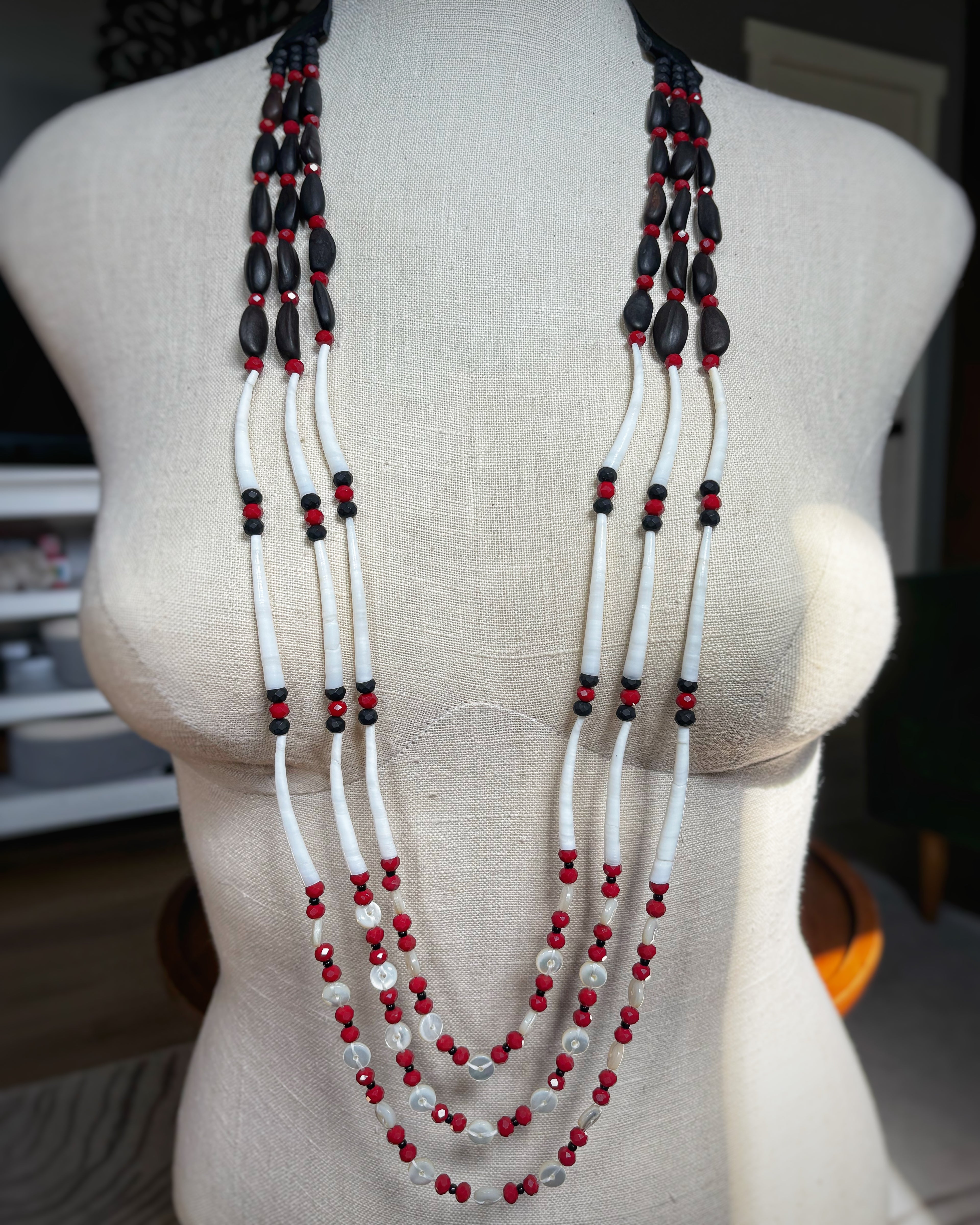 Three Strand Red and Black Pinenut and Dentalium Necklace featuring layered natural beads in vibrant red, black, and white tones