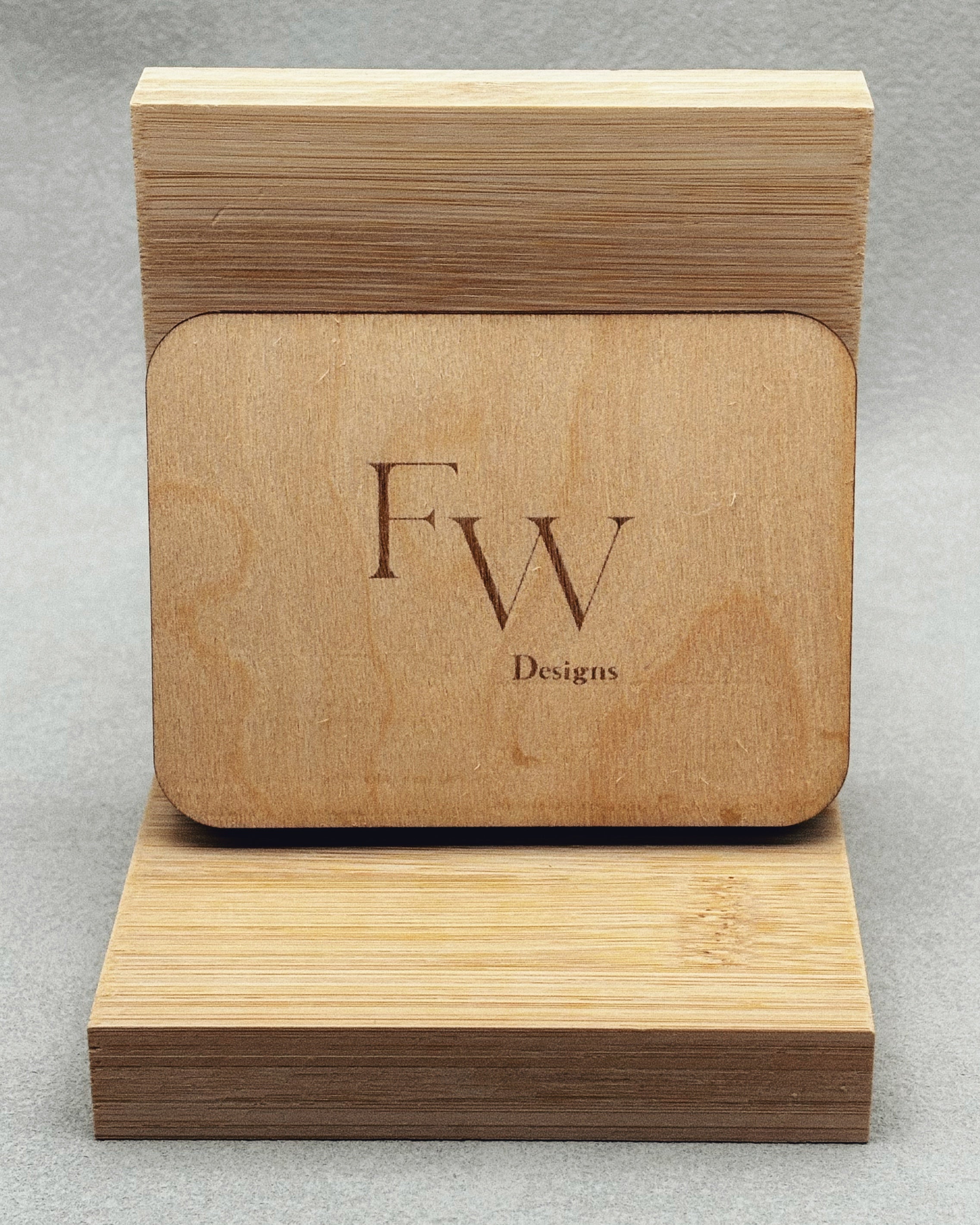 Needle Keepers wooden box engraved with FW Designs logo on smooth natural wood, displayed on a bamboo stand