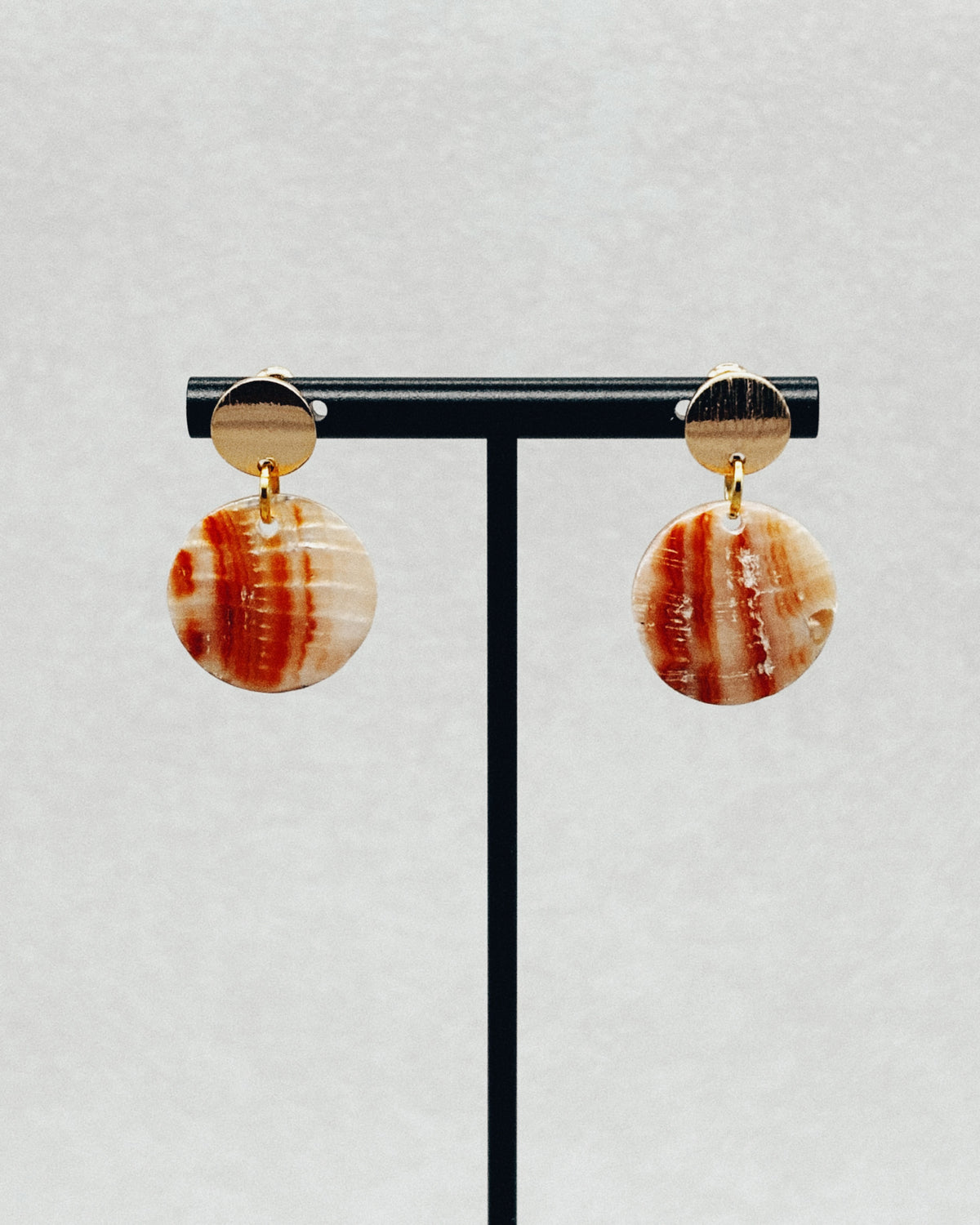 Red Abalone Textured Gold Studs with round red abalone stones and textured gold tops against a neutral background