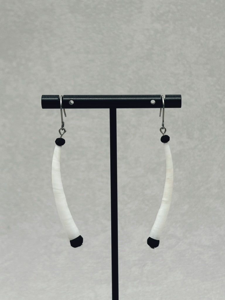 Black Dentalium Dangles hanging on a black display stand against a neutral gray background