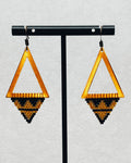 Bronze Triangle Dangles with open bronze frames and handcrafted black and gold geometric bead patterns hanging on display stand
