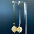 Faceted Abalone Drops with iridescent coin shells hanging from delicate gold threader chains on clear acrylic stand