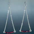 Red Silver Chain Drops featuring delicate silver chains with faceted glass red beads hanging against gray background