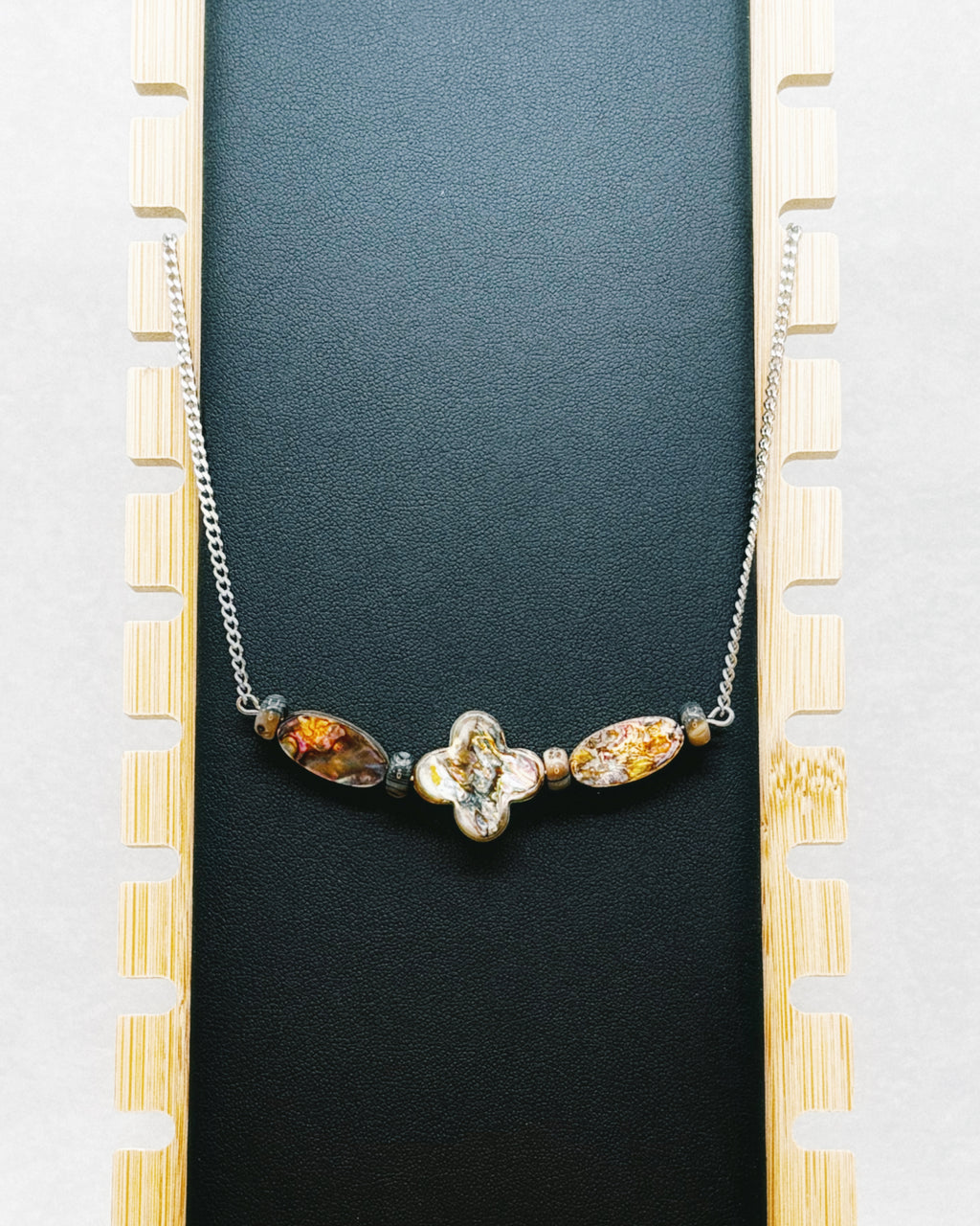 Abalone Quatrefoil Set featuring iridescent quatrefoil centerpiece and two amber-toned oval beads on silver chain