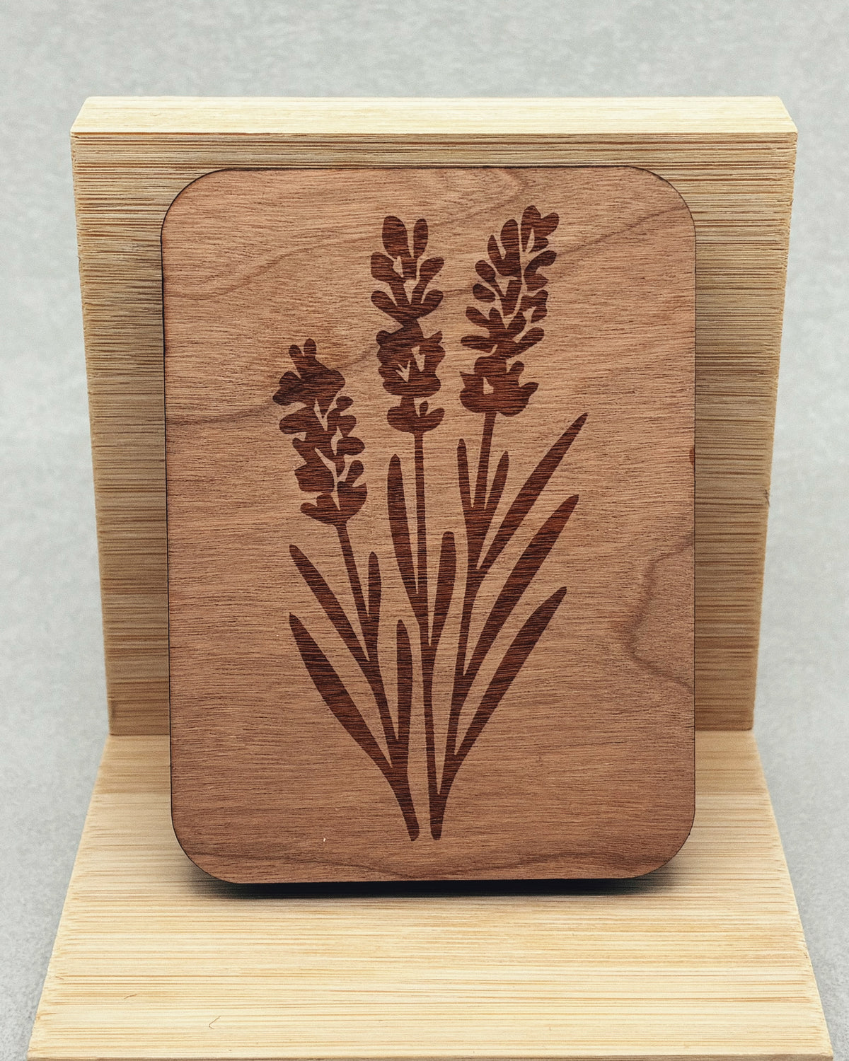 Needle Keepers wooden needle holder with engraved floral design on a natural wood stand