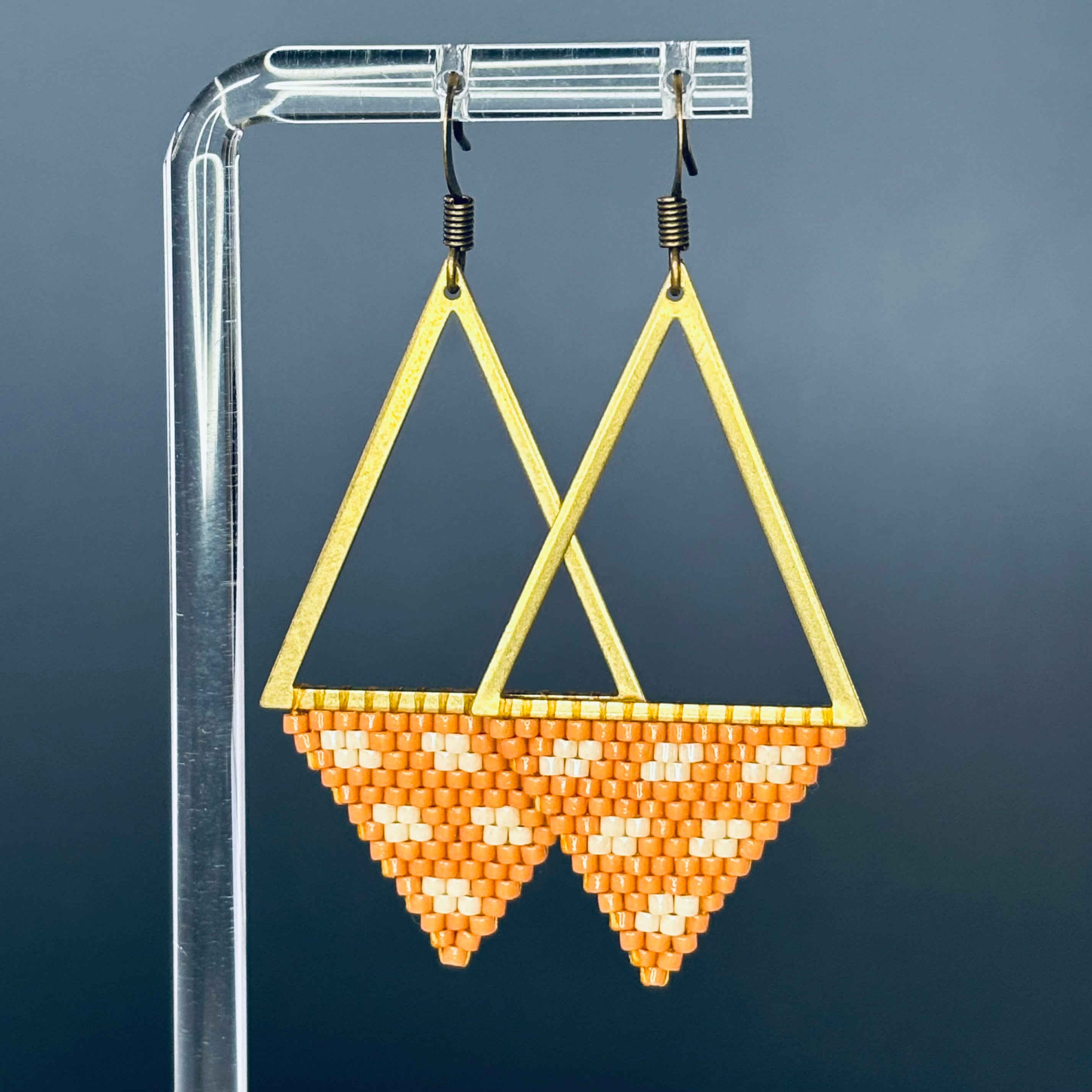 Bronze Triangle Dangles featuring open bronze triangular frames with orange and cream handmade beaded patterns
