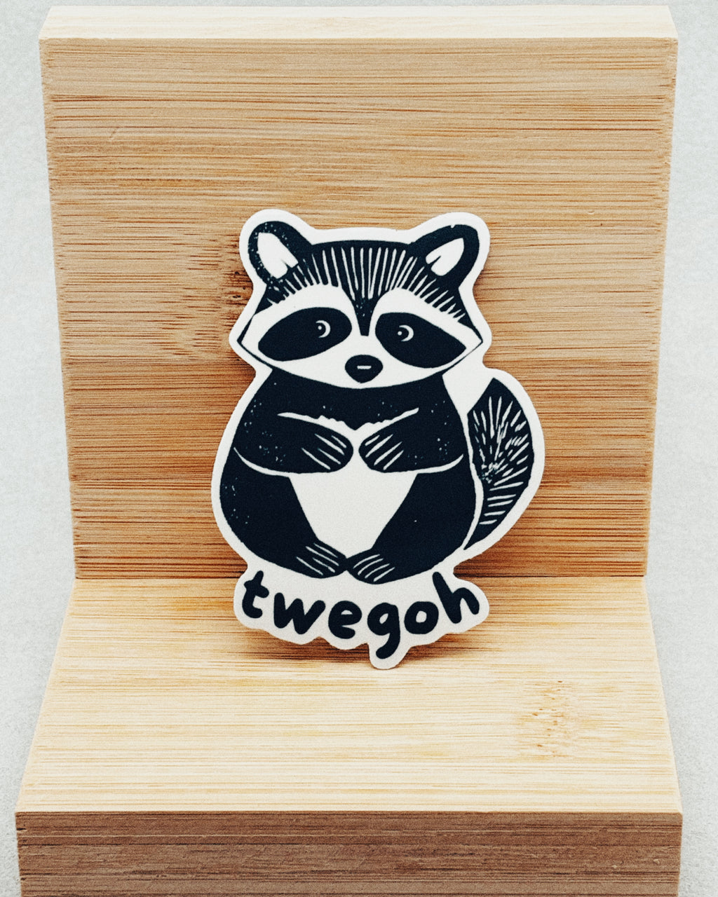 Yurok Vocabulary Stickers showing a black and white raccoon illustration with the word "twegoh" on a wooden background