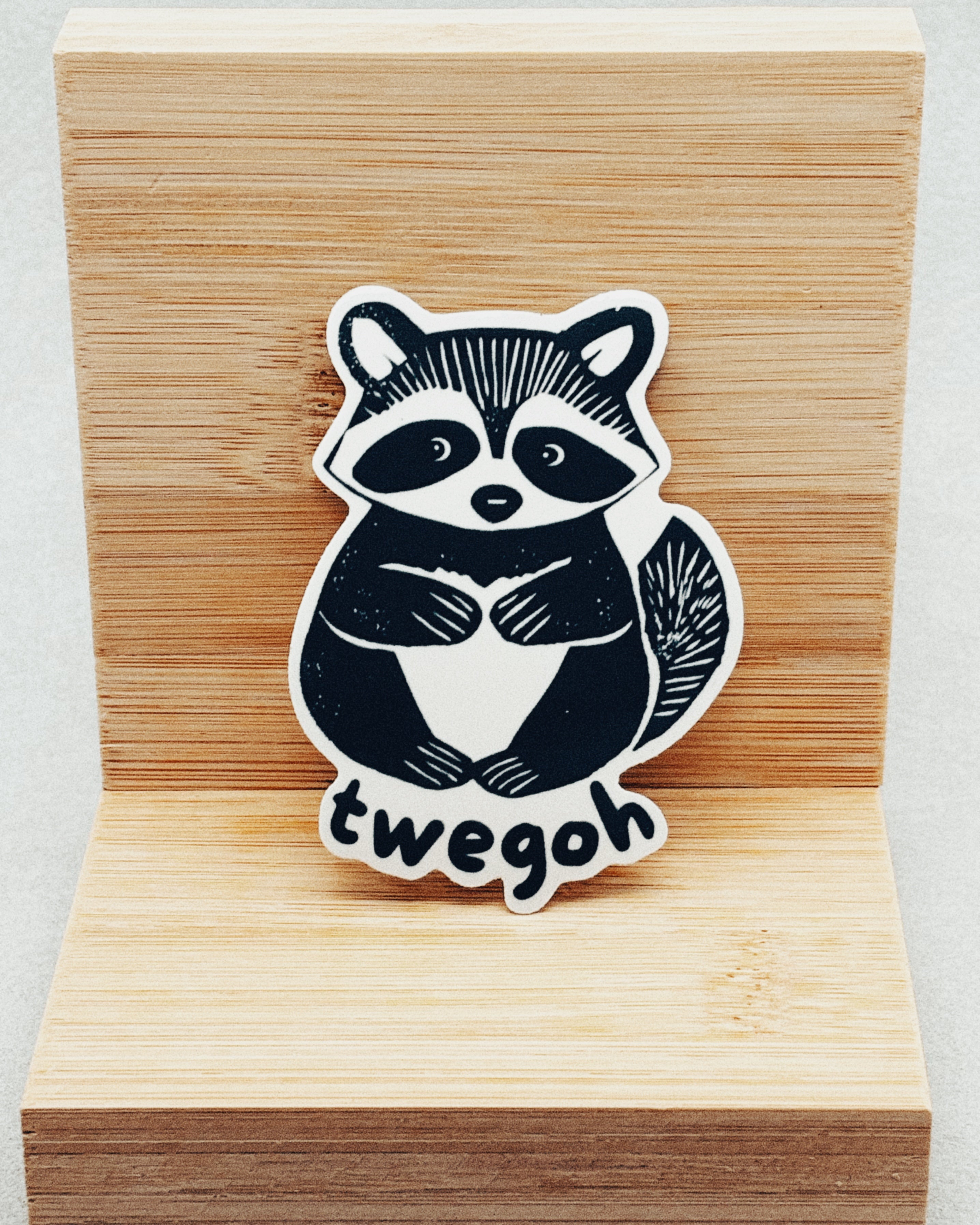 Yurok Vocabulary Stickers showing a black and white raccoon illustration with the word "twegoh" on a wooden background