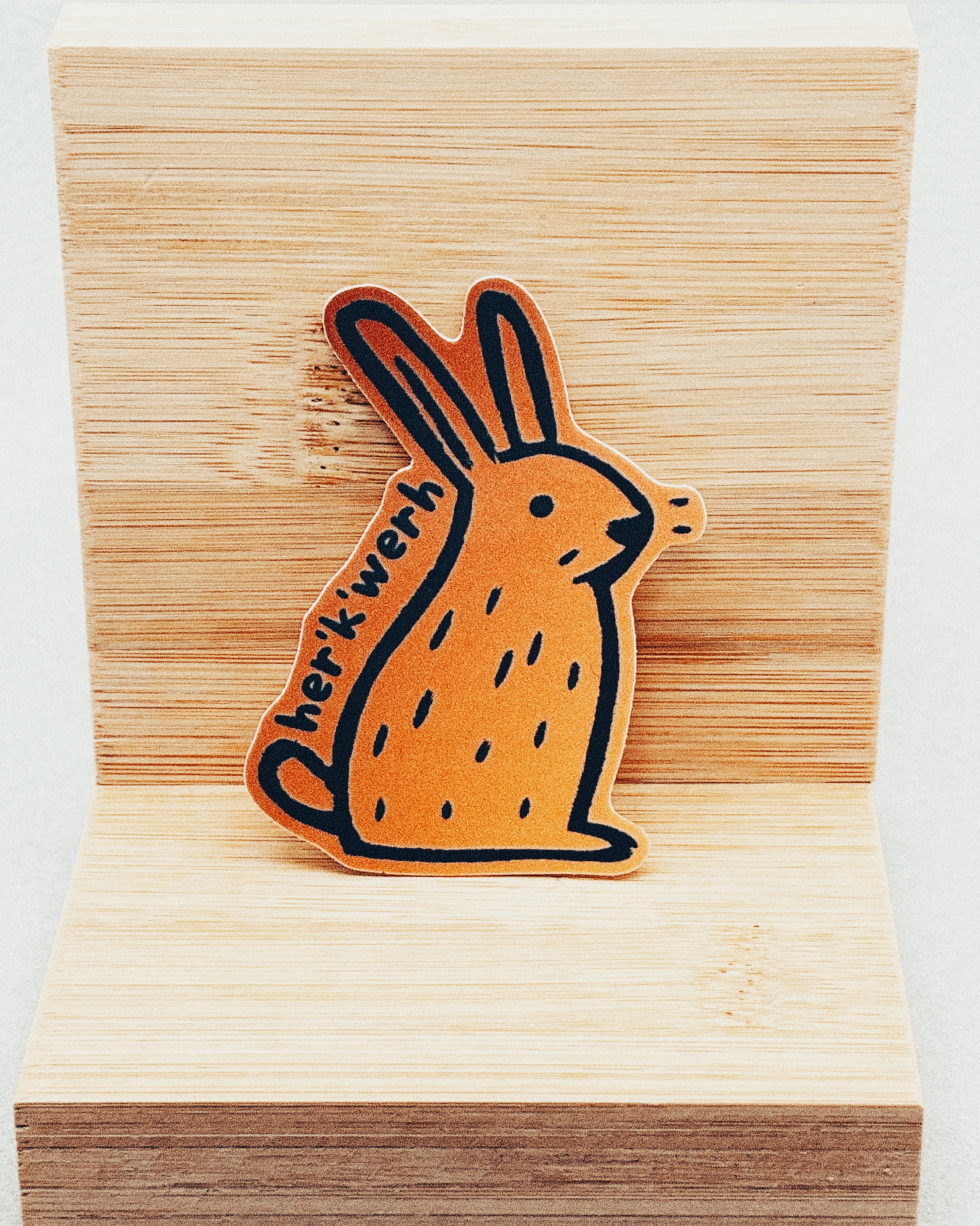 Yurok Vocabulary Stickers showing an orange rabbit illustration with black line details and Yurok word "herikwerh" on wooden background