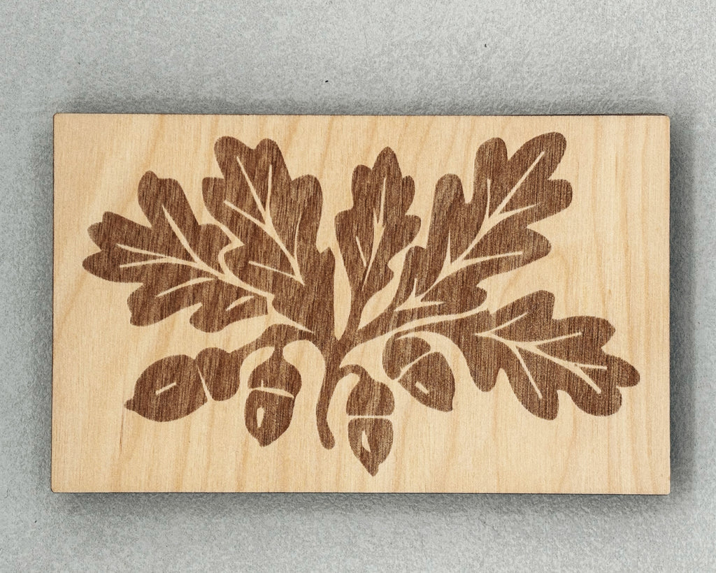 Scissor Keepers with engraved oak leaves and acorns design on smooth light wood background