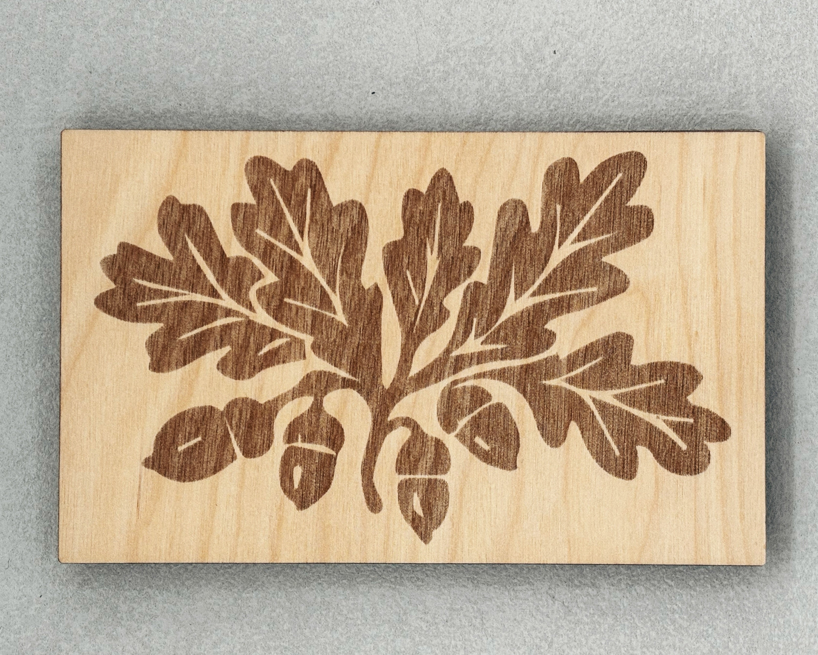Scissor Keepers with engraved oak leaves and acorns design on smooth light wood background