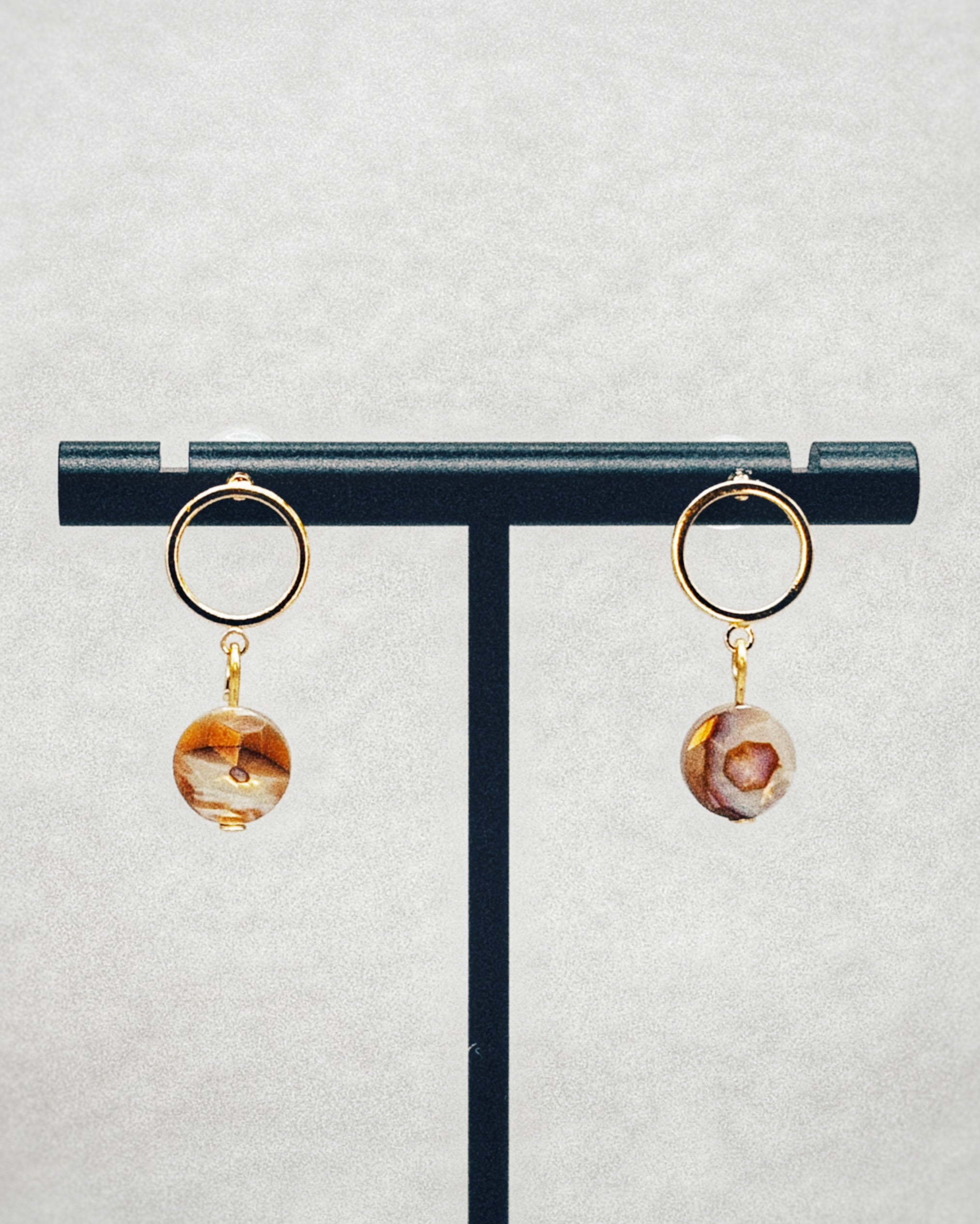 Faceted Abalone Gold Open Circle Studs with natural abalone stone drop on gold-tone open circle studs displayed on stand