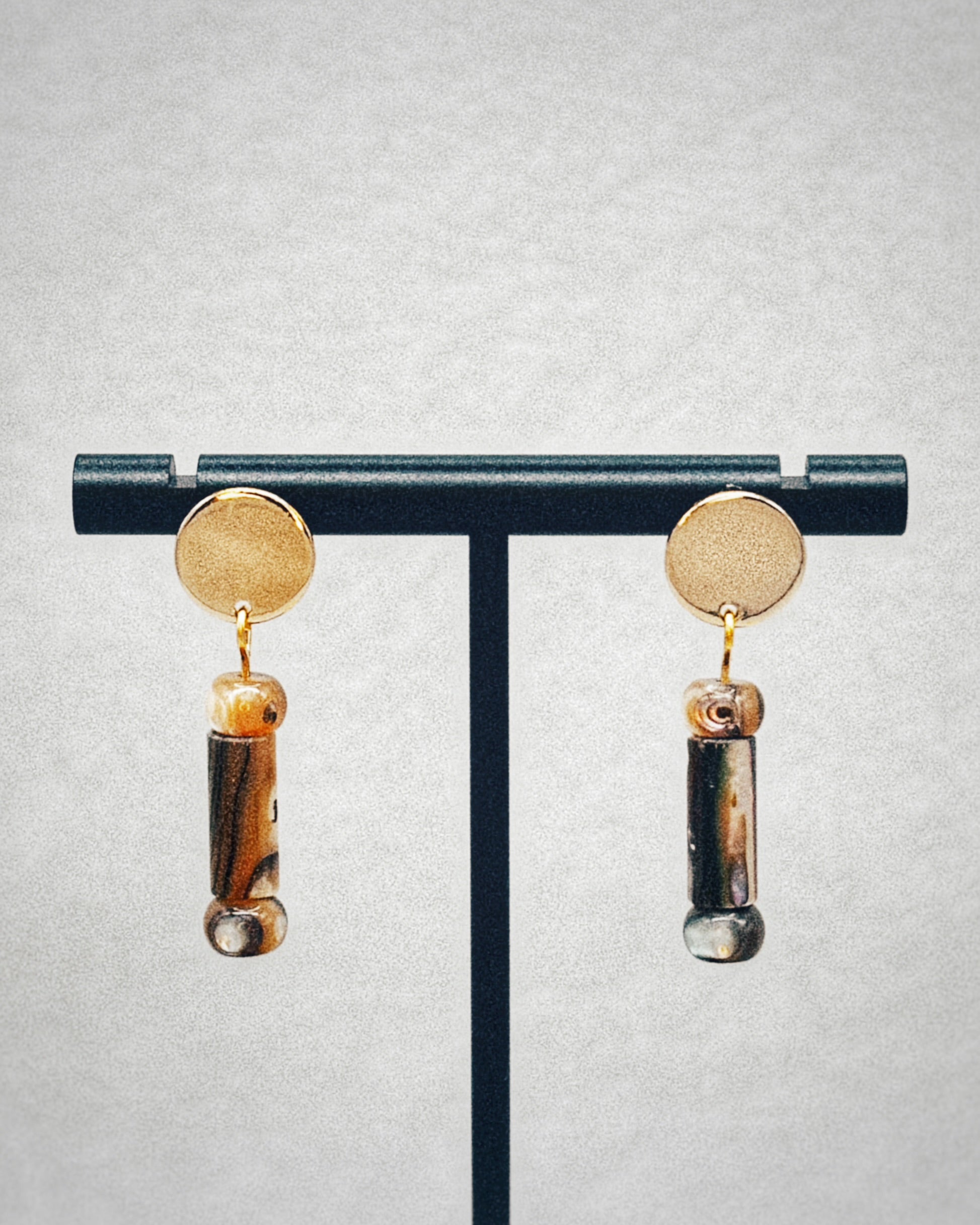 Abalone Cylinder Gold Circle Studs with polished gold discs and natural abalone cylinder drops on a black stand display