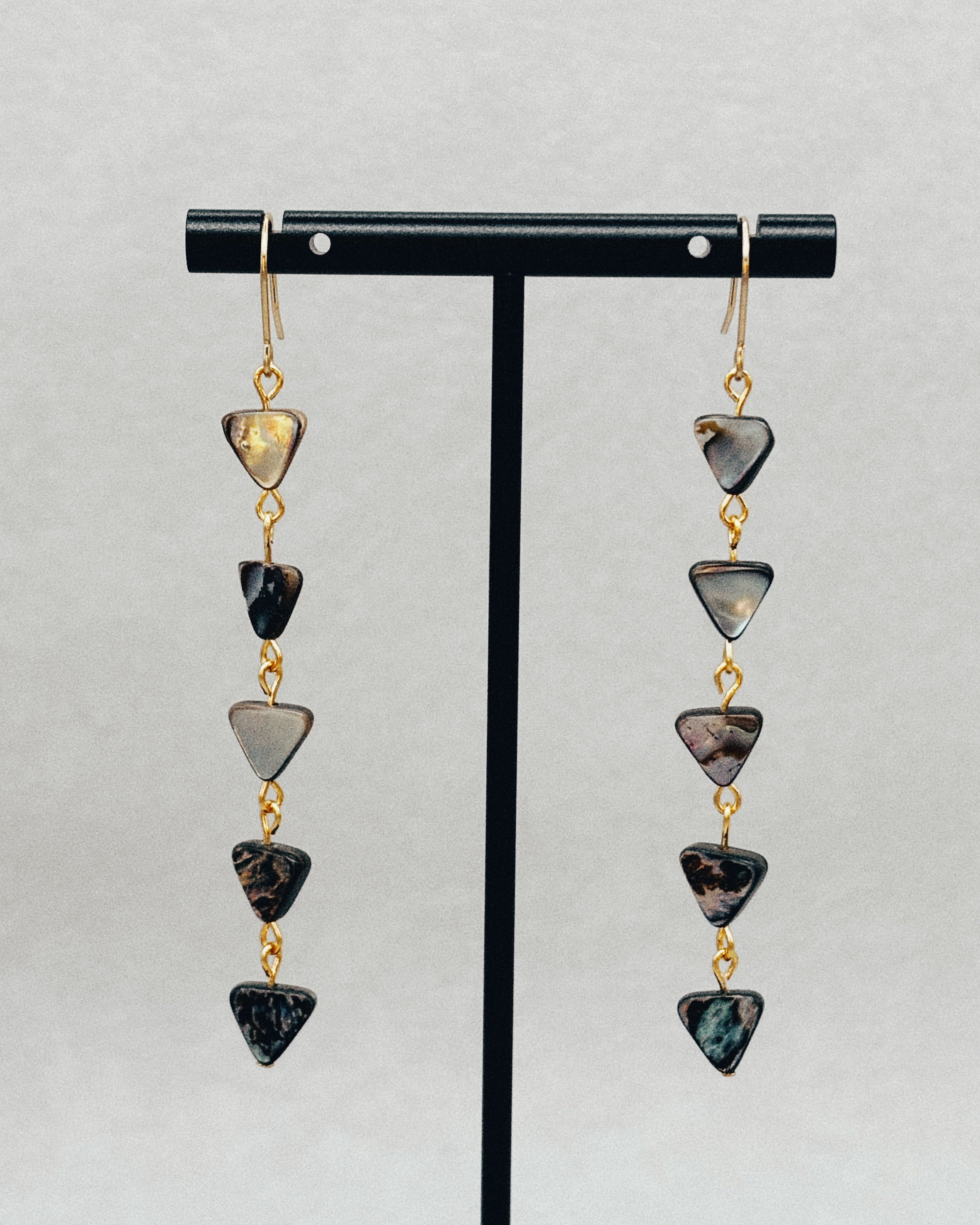 Long Abalone Triangle Dangles featuring five dark iridescent triangular shells linked with gold accents, hanging elegantly.