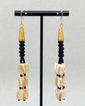 Mother of Pearl and Matte Glass Bead Dangles featuring gold accents and handcrafted black and pearl beads on display stand.