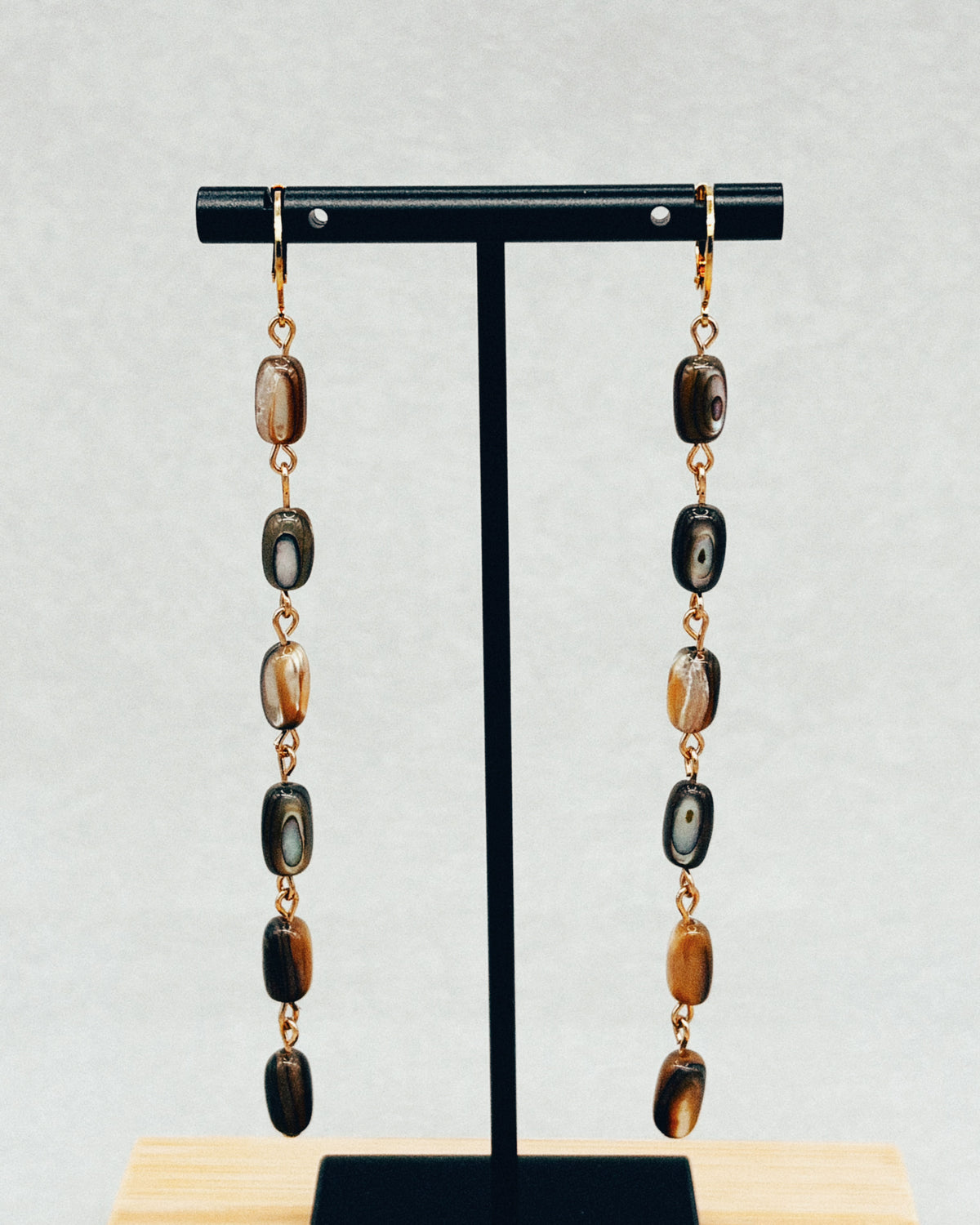 Abalone Nugget Dangles with iridescent stone beads displayed on a black jewelry stand
