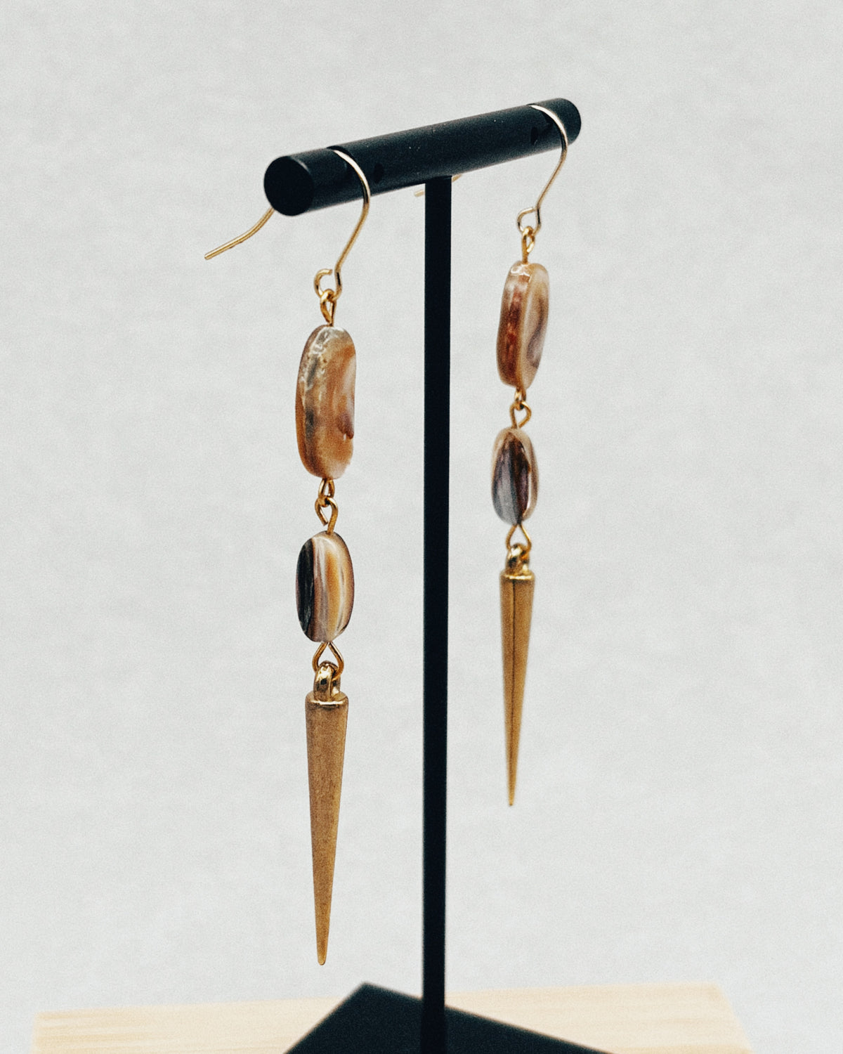 Double Abalone Spike Dangles with abalone beads and long tapered spikes on a black display stand