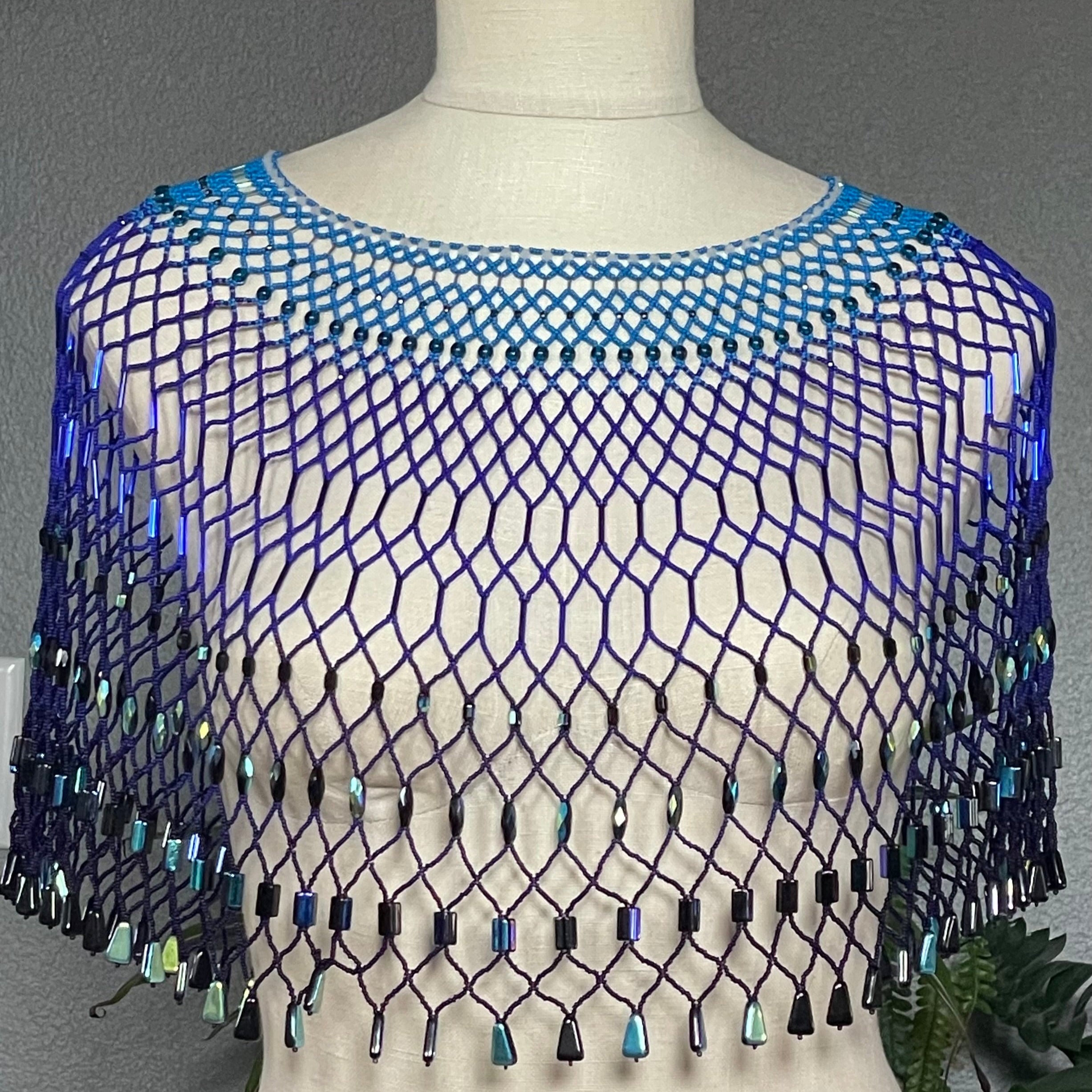 Blue beaded netting on a mannequin against a gray background